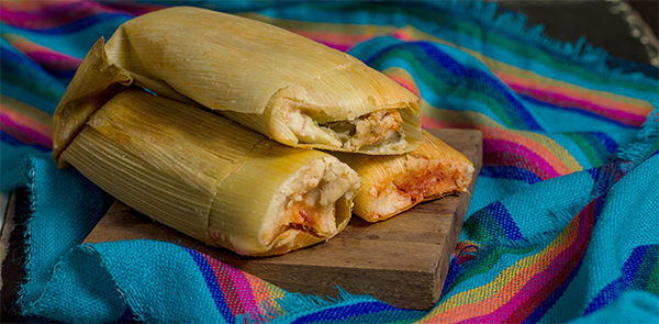 INELDA artilce Image - Working With Grief and Loss During the Holidays - Home made Tamales on a wood block cutting board setting on a Mexican heritage print cloth